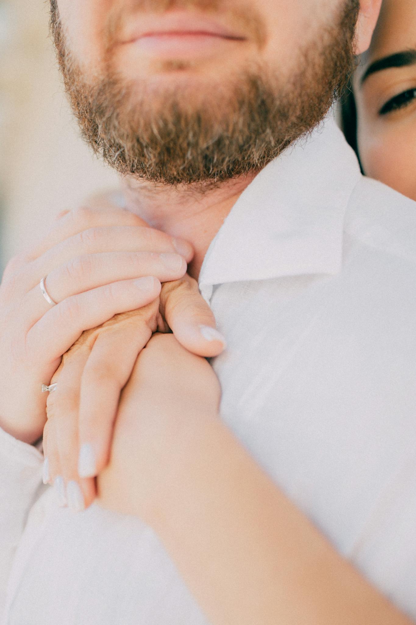 A close-up shot of a couple embracing with gentle hands and warm expressions.